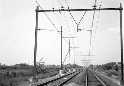 803832 Gezicht op de spoorlijn bij Deurne, met een speciale constructie van de bovenleiding, waarbij de draagkabel ...